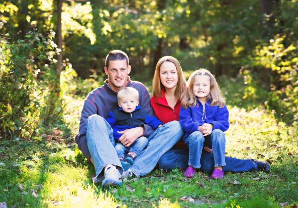 Nate and Dena Brockhouse, the owners of Brockhouse Well & Pump, with their children posing for a photo in a well lit field